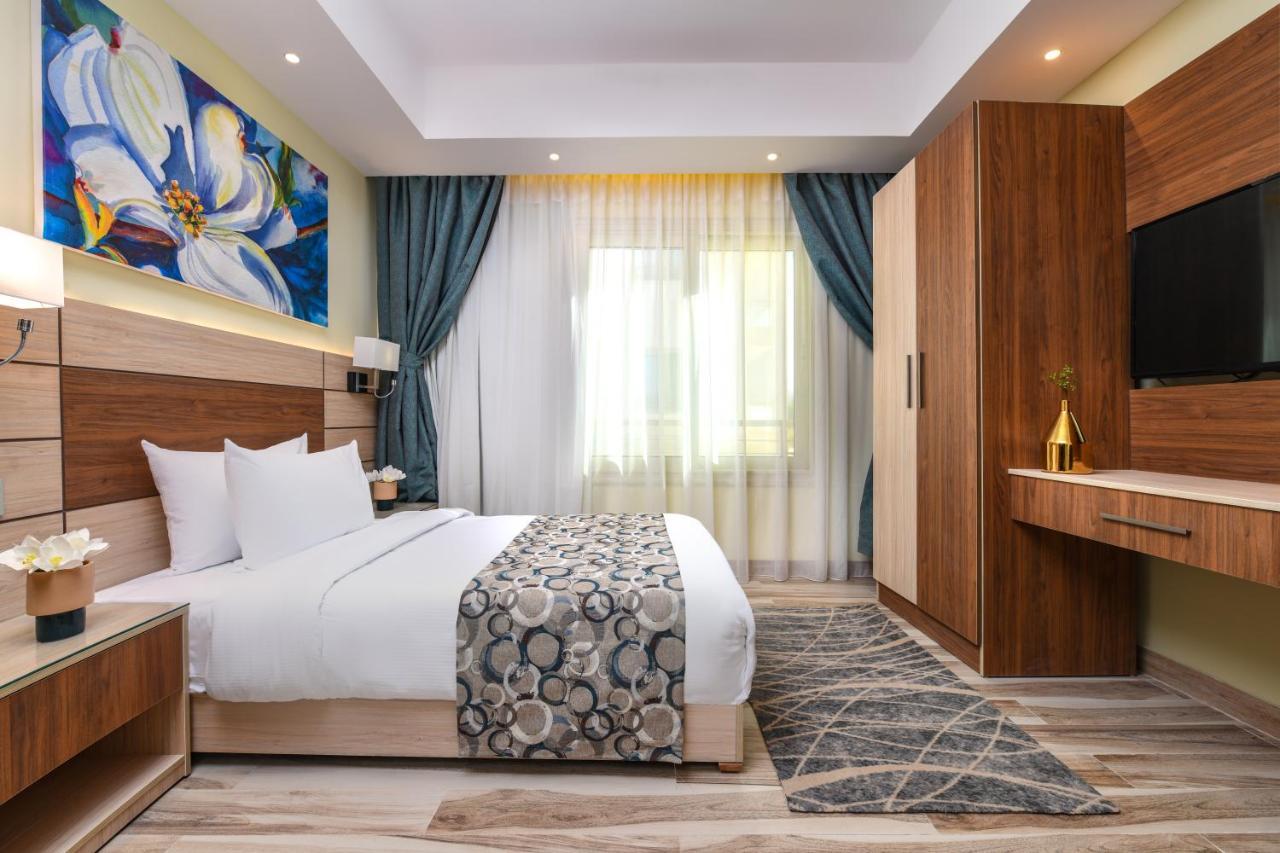 Tolip Resort El Galala Majestic Ain Sukhna Exterior foto The photo shows a well-designed hotel room. It features a comfortable bed with a decorative bedspread and two pillows. There are soft curtains framing a window that lets in natural light. On one side, there is a colorful piece of artwork hanging on t