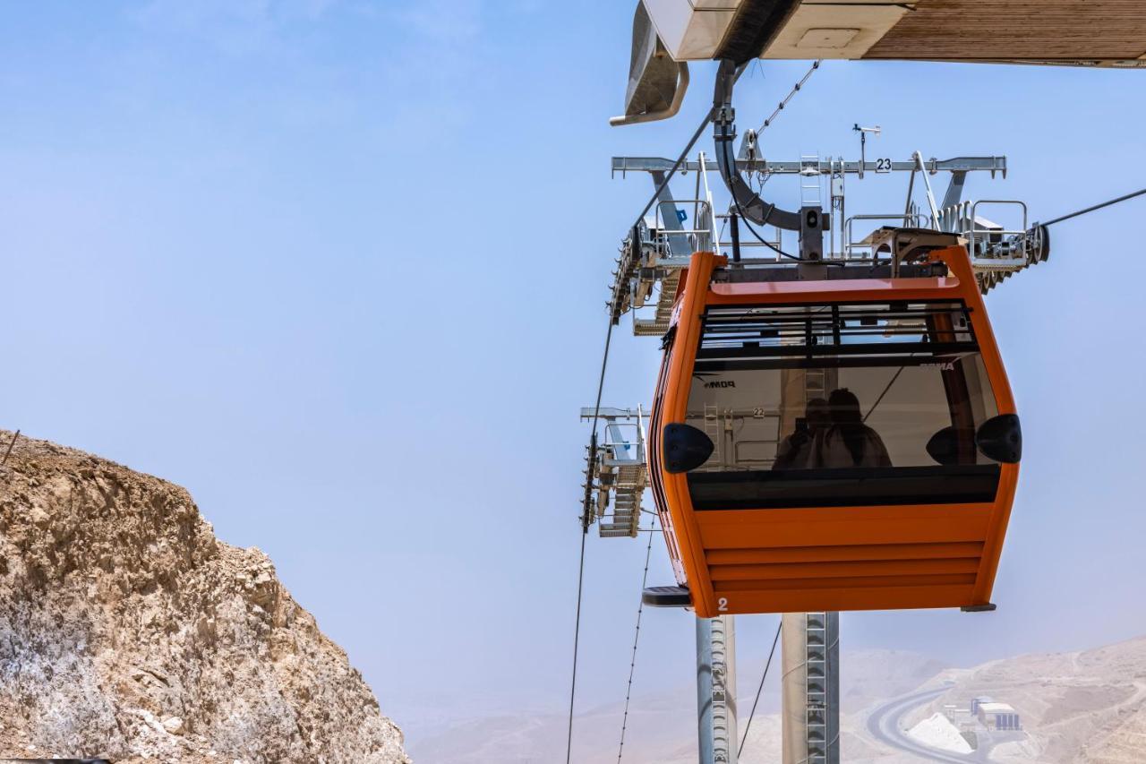 Tolip Resort El Galala Majestic Ain Sukhna Exterior foto The photo shows an orange gondola or cable car hanging on a cable system. The gondola appears to be suspended in the air above a rocky landscape, with a clear sky in the background. There are supporting cables and structures visible, indicating that 